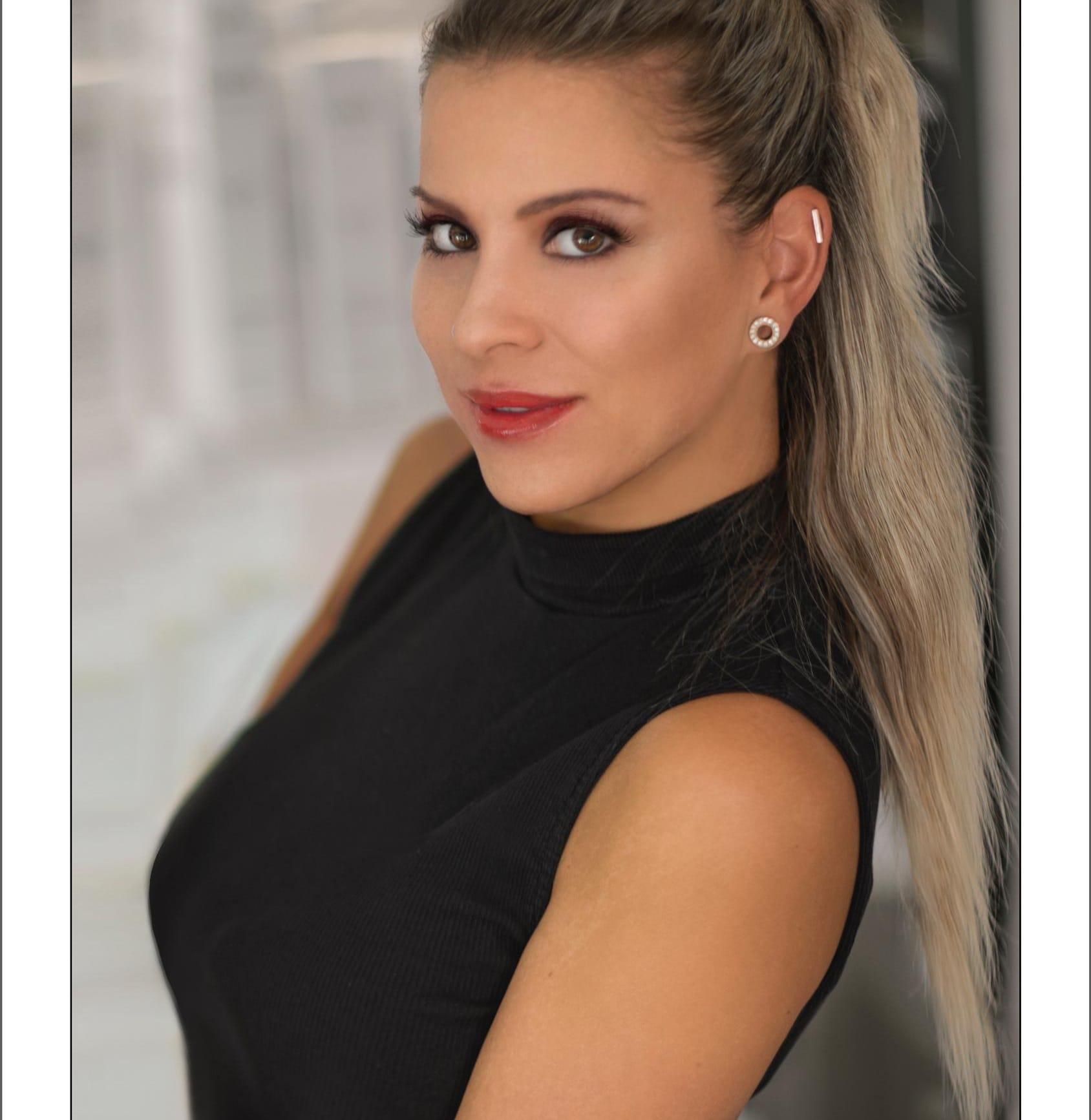 /Frau mit auffälligem Make-up und Ohrringen vor verschwommenem Hintergrund.