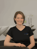 /Frau mit braunen Haaren in schwarzem Oberteil Hintergrund mit Orchideen.