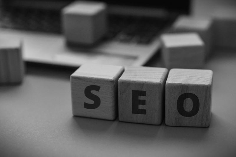 Schwarzweissbild von Holzklötzen mit SEO-Text vor einem Laptop