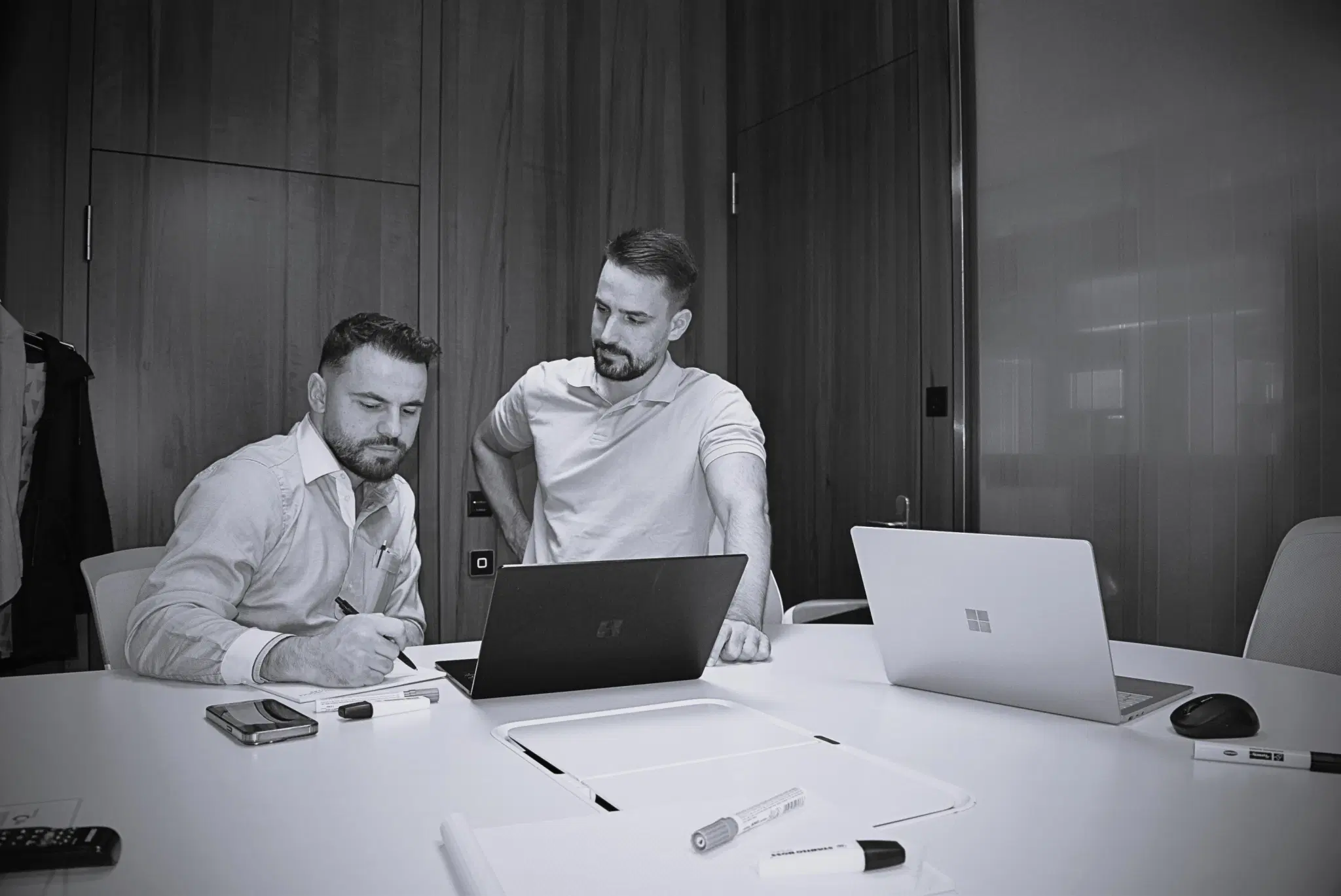 Zwei Männer arbeiten in einem Büro Laptops und Schreibwaren auf dem Tisch.